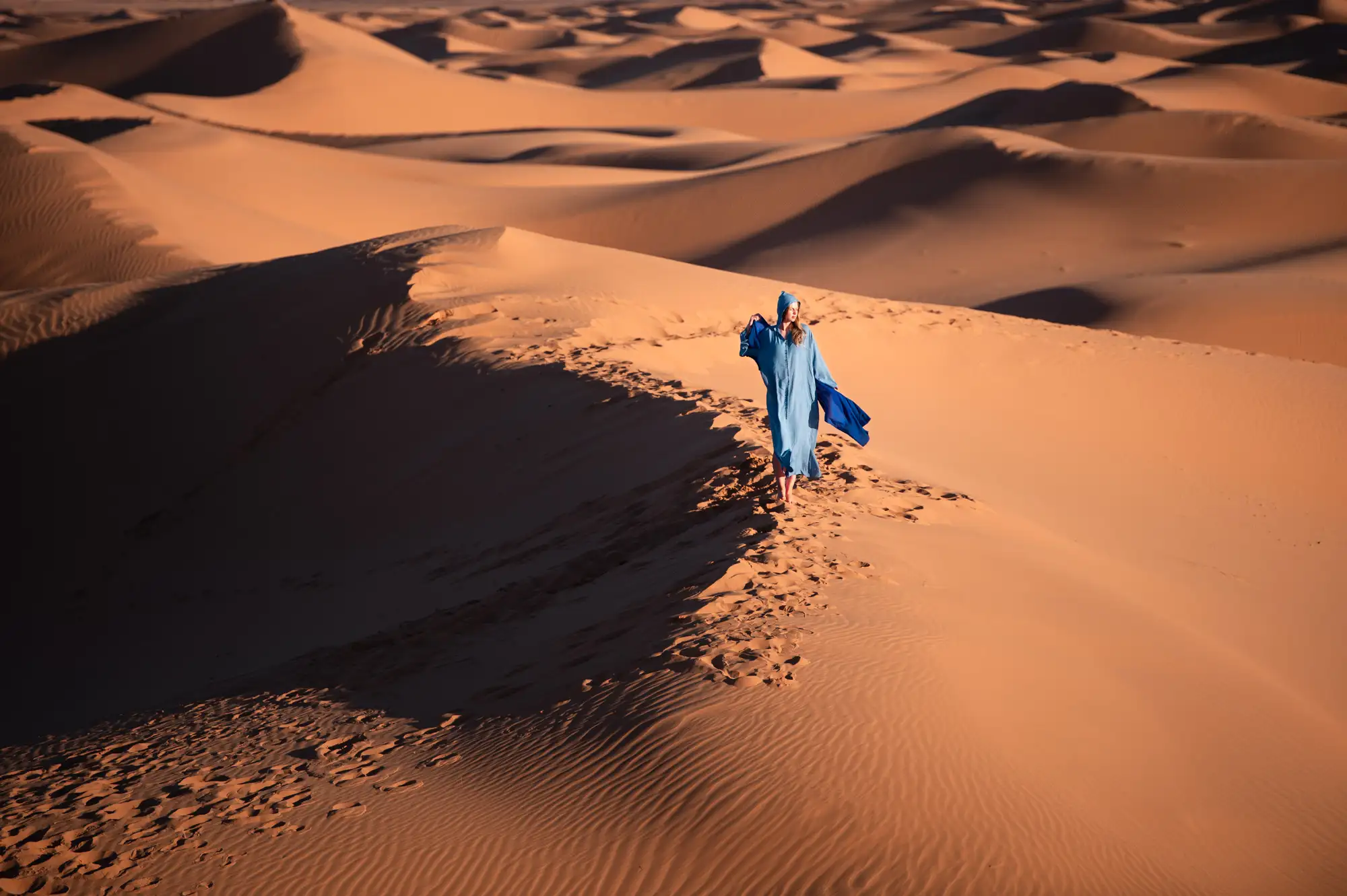 Traveler walking across desert dunes